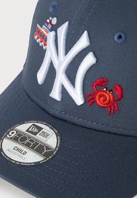 Tamna plava dječja kapica za bejzbol s bijelim "NY" logotipom, izvezenim crvenim rakom i malim dizajnom broda u narančastoj i plavoj boji.