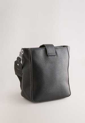 Czarna skórzana torba o teksturowanej powierzchni, prostokątnym kształcie, z górnym uchwytem i odpinanym paskiem na ramię. Posiada kontrastowe przeszycia oraz metkę.