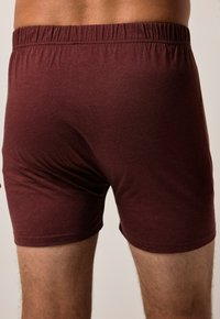 Boxer fit in bordeaux con una texture morbida e elastico in vita, con cuciture lisce e una vestibilità aderente intorno alle cosce.