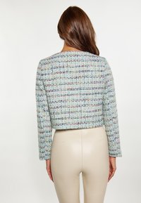 Zkrácená bunda z mnohobarevné tkaniny tweed s texturovaným, tkaným vzorem. Obsahuje dlouhé rukávy a kulatý výstřih.