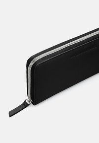 Black leather wallet with silver zipper. Rectangular shape, smooth texture, and a simple design. Features a branded detail on the side.