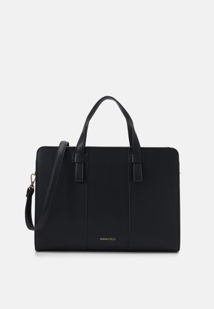 Zwarte synthetische tote bag met dubbele handvatten en een afneembare schouderriem. Bevat een gouden logo aan de onderkant en heeft een gestructureerde rechthoekige vorm.