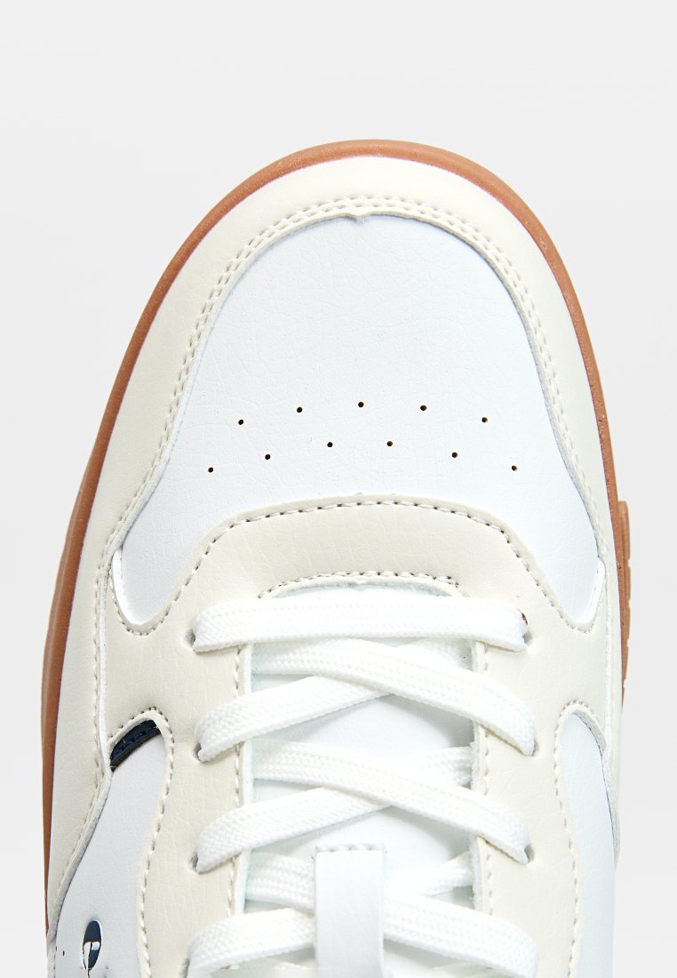 Weiße Leder-Sneaker mit einer strukturierten Oberfläche, flachen weißen Schnürsenkeln und einer braunen Gummisohle. Perforationsdetails im Bereich der Zehen.