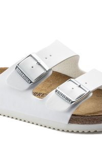 Sandali Birkenstock bianchi con due fibbie regolabili, footbed in sughero e suola in gomma testurizzata. Presentano un materiale superiore liscio e un colore chiaro.