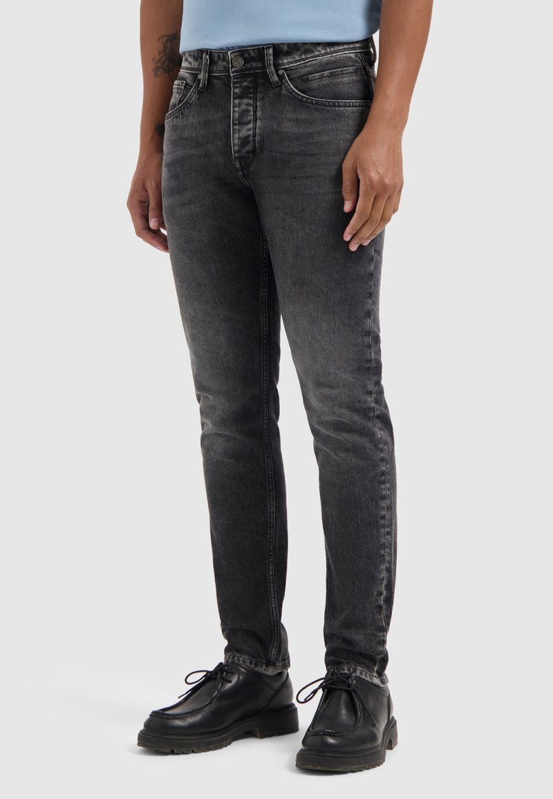 Zwarte denim jeans met een slim fit, vervaagde afwerking, vijf-pocket ontwerp en metalen knopen. Draagt met zwarte schoenen.