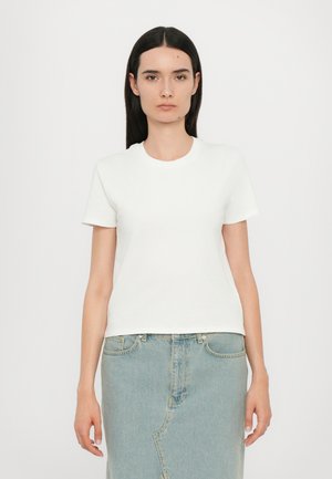 T-shirt bianca in cotone a maniche corte con collo rotondo, abbinata a una gonna in denim azzurro chiaro con cuciture a vista e silhouette dritta.