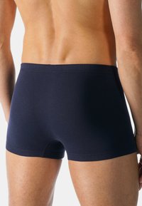Boxer-briefs en coton bleu marine avec une coupe ajustée et une ceinture élastique, présentant une texture lisse et un ourlet soigné.