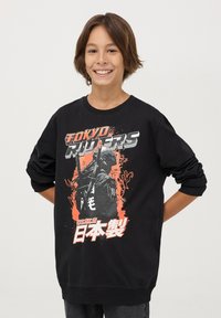 Czarny sweatshirt z graficznym nadrukiem postaci z bronią, pomarańczowymi akcentami oraz napisem "Tokyo Riders" w kolorze srebrnym i czerwonym.