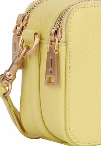 Bolso amarillo texturizado con herrajes en tono dorado, dobles cremalleras y una correa desmontable. Presenta una forma elegante y compacta y un diseño estructurado.