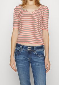 Röd- och grönrandig kortärmad, figursydd topp med V-ringning, parat med blå denimjeans med en klassisk design och tvåknäpps stängning.