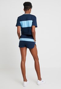 Marineblaue Baumwoll-T-Shirt mit hellblauen horizontalen Streifen, kombiniert mit passenden Shorts. Der Stoff wirkt weich und hat ein lässiges Design.