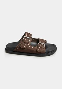 Infradito in suede marrone con doppie cinghie regolabili, fibbie in tonalità argento e borchie metalliche, caratterizzati da una suola in gomma nera.