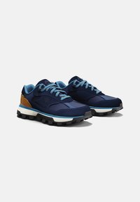 Zapatillas azul marino con parte superior texturizada, cordones azul claro y un acento marrón. Presentan una suela negra resistente y una entresuela acolchada.
