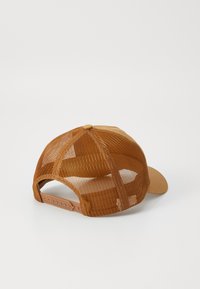 Brun hatt med solid front og netting bak. Har en buet skjerm, justerbar stropp og en knapp på toppen.