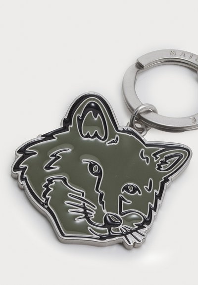 Porte-clés avec une tête de loup en émail vert avec des contours noirs, attaché à un anneau en métal argenté. Texture lisse, design simple.
