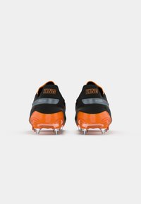 Scarpe da calcio nere e arancioni con un design elegante, caratterizzate da una punta arancione lucida e spine visibili per la trazione. "KING" è stampato sul tallone.