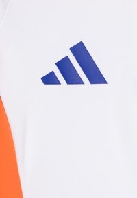 Weißes Sportshirt mit orangefarbenem Einsatz, glatte Stoffoberfläche, mit einem blauem Drei-Streifen-Logo, das deutlich sichtbar ist.
