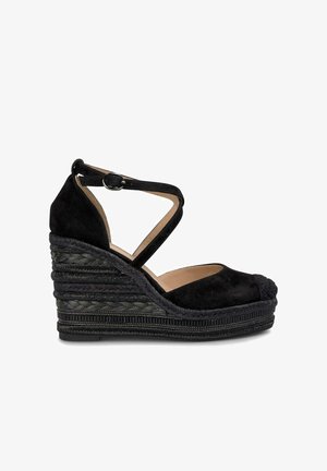Black suede wedge shoe with a cross strap design, rounded toe, and a textured braided jute platform for added height.
