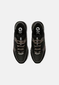 Zwart-grijze sportschoenen van mesh en suède materiaal, met ronde veters, zilveren accenten en een logo op de tong.