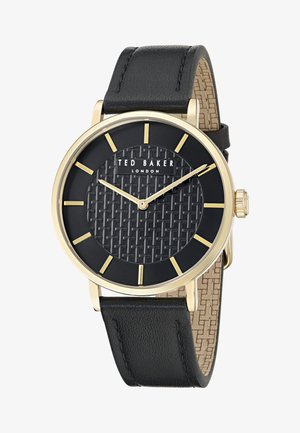 Melna ādas siksniņa pulkstenim ar zeltīta metāla korpusu, strukturētu melnu seju, zeltītām stundu atzīmēm un zīmola logo. Pievilcīgs pinuma raksts.