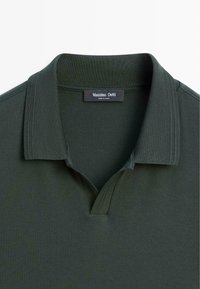 Polo vert foncé avec un col côtelé et sans boutons, avec une étiquette de la marque « Massimo Dutti » à l'intérieur de l'encolure.