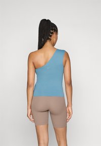 Blå, en- skulder atletisk topp laget av glatt stoff, sammen med brune, tettsittende shorts. Har en liten Nike-logo på baksiden.