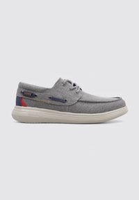 Zapatos casuales grises con parte superior de lona, punta redonda, suela blanca y acentos en contraste en azul marino y rojo. Presentan cordones grises y costuras decorativas.