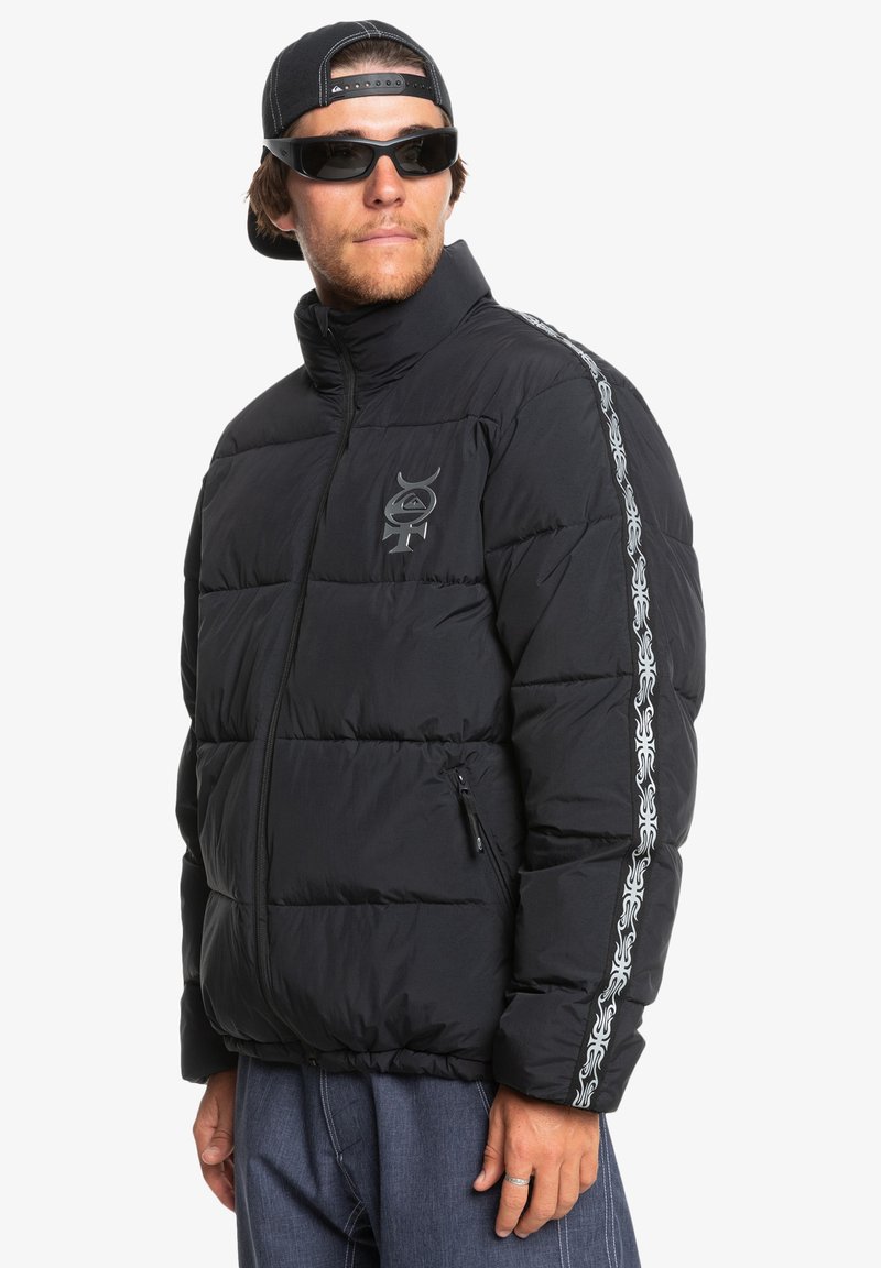 Czarna kurtka puchowa z wysokim kołnierzem, z kieszenią na zamek i dekoracyjnym białym wzorem na rękawie. Wykonana z pikowanego materiału.