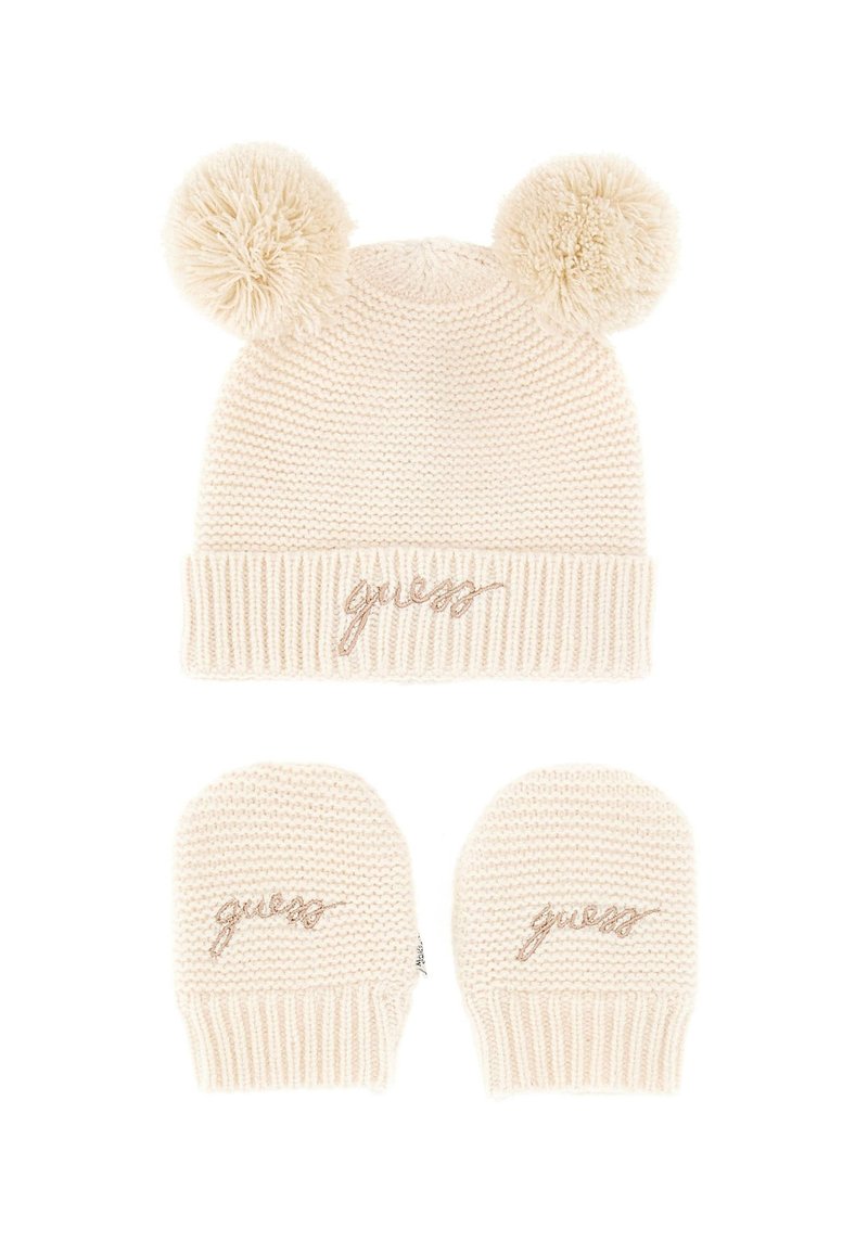 Beanie in maglina crema con due pom-pom e un bordo a coste, con ricamo "guess" in oro rosato. Inclusi un paio di guanti a maglia abbinati.