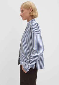 Gestreiftes Hemd mit Knöpfen, das dünne blaue und weiße vertikale Streifen, lange Ärmel und eine lockere Passform aufweist. Texturierter Baumwollstoff mit klassischem Kragen.