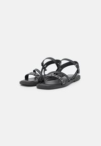 Svarta sandaler med flera remmar, med ett texturerat, glänsande band. Platt sula med minimalistisk design, justerbar ankelrem.