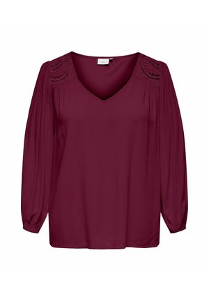 Burgundy blouse with a V-neck and long sleeves. Features intricate lace detailing on shoulders and a smooth, lightweight fabric.