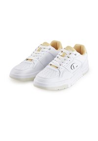 Witte sportieve sneakers met een gladleren bovenwerk, geperforeerde neus, gevoerde kraag en een getextureerde rubberen zool met crèmekleurige accenten.