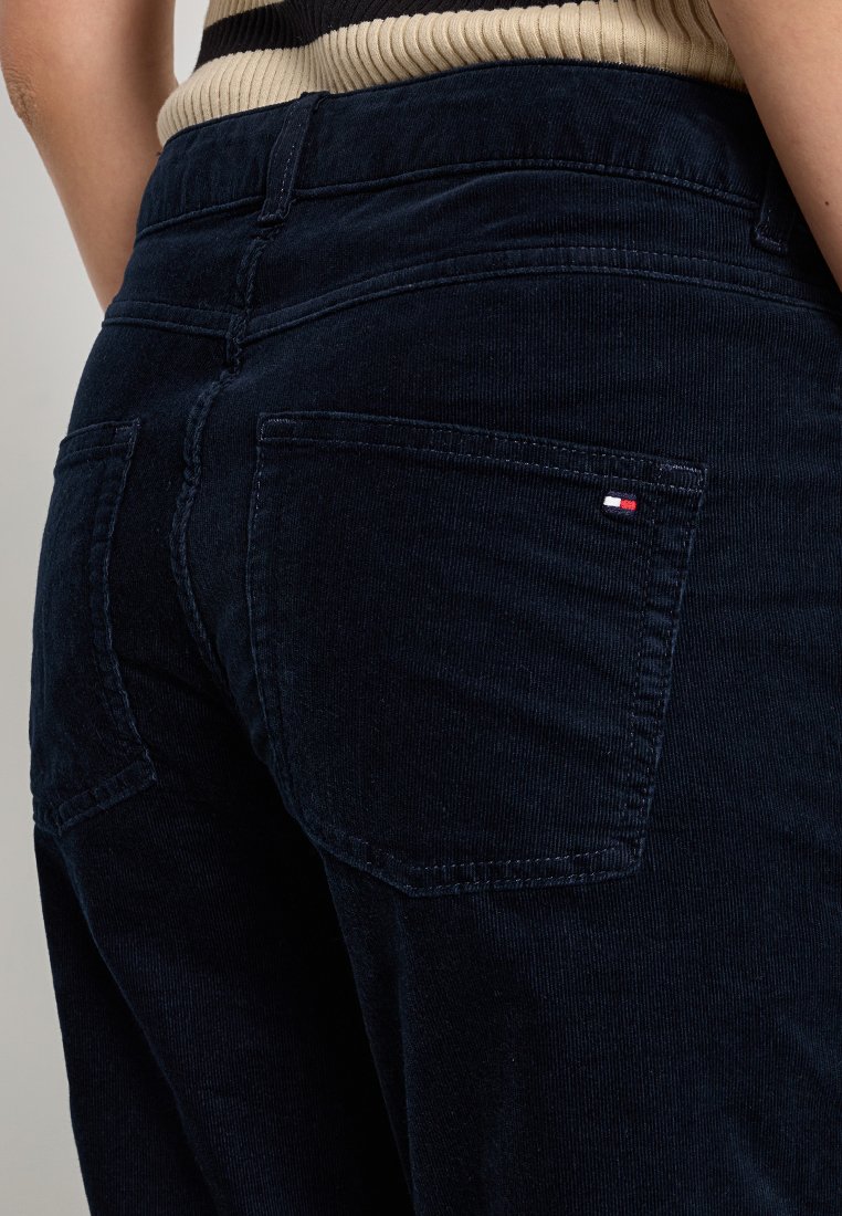 Dunkelblaue Cordhosen mit einer taillierten Passform, ausgestattet mit zwei Gesäßtaschen und einem kleinen Logodetail in Rot, Weiß und Blau an der rechten Tasche.