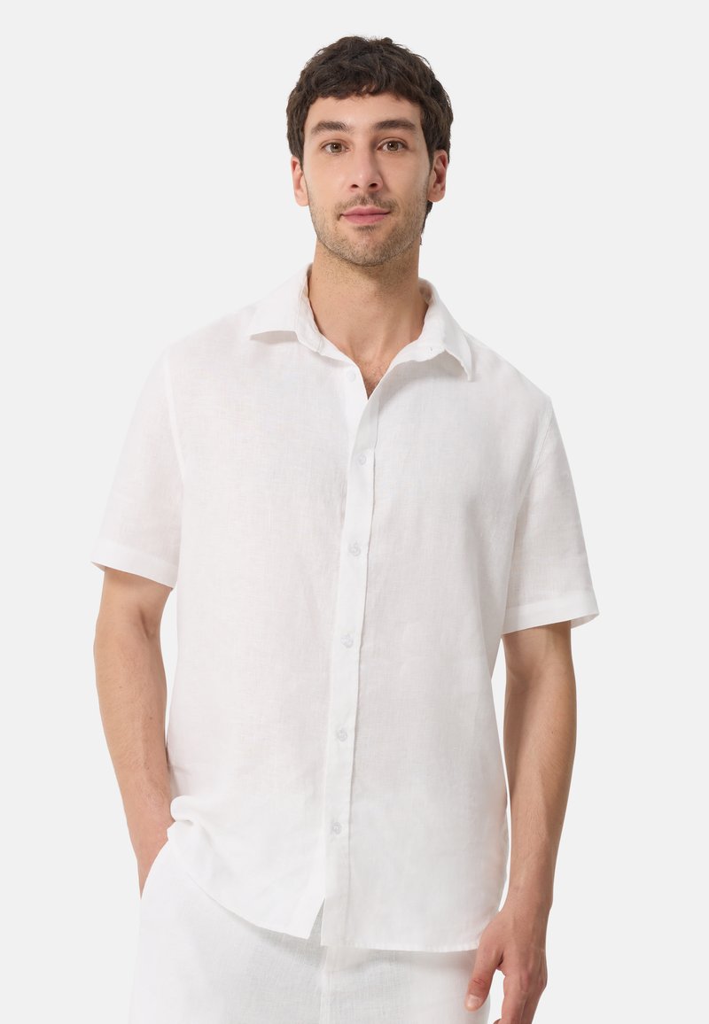 Chemise courte à manches blanches en lin avec un devant boutonné, un col étalé et une coupe décontractée, présentant une texture subtile.
