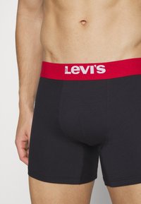 Levi's svarta boxershorts med en röd elastisk midjeband med logotyp. Har en kroppsnära design och mjukt tyg för komfort och flexibilitet.