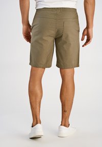 Szorty khaki z elastycznym pasem, tylną kieszenią i luźnym krojem, zestawione z białymi trampkami. Miękki, gładki materiał.