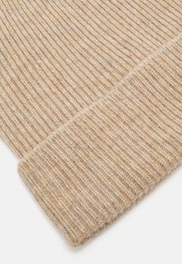 Ribbed knit-sweater cuff made of light beige yarn, featuring a soft texture and a clean finish at the edge.