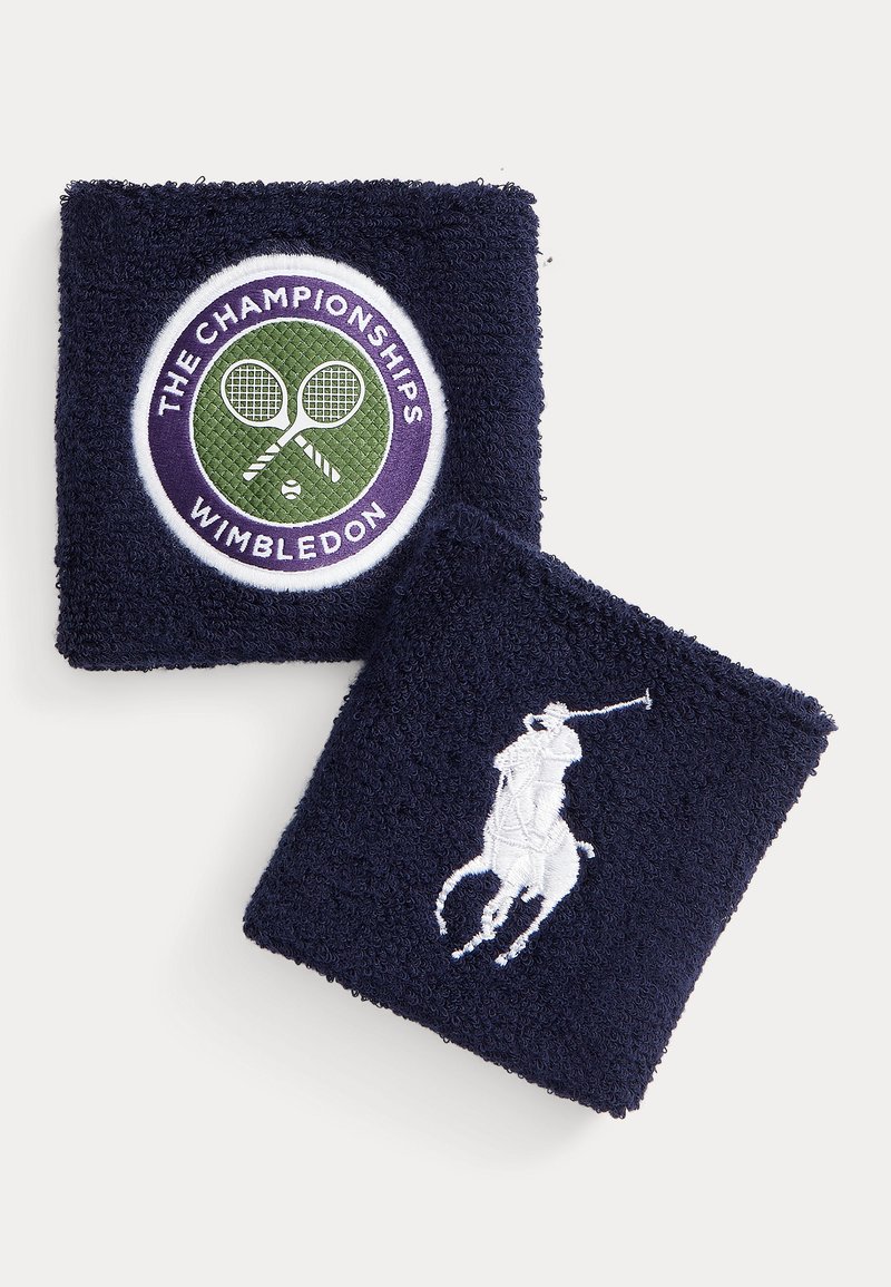 Marineblå bomullsterry håndleddsbånd med brodert logo av tennisracketer og "The Championships Wimbledon" samt et hvitt poloselgerdesign.