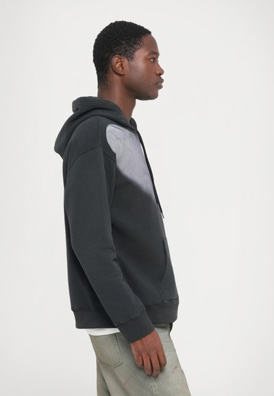 Kapuca sivi pulover, ki ima svetlo sivo ploščo na prsih, izdelan iz mehkega blaga, z ohlapnim krojem in sprednjim žepom.