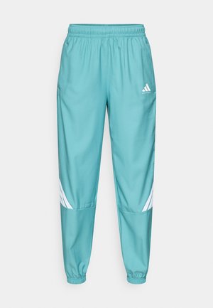 Teal sportbroek met elastische tailleband, voorzien van witte diagonale strepen op de onderbenen en zijzakken. Gemaakt van lichtgewicht materiaal.