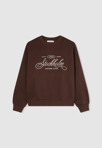 Felpa marrone con collo a girocollo a coste e maniche lunghe. Presenta una stampa bianca: "Stockholm Leisure Club" e "North 1985 Europe."