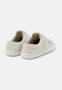 Sneaker bianco in pelle con ricami floreali in blu e arancione, texture morbida, punta tonda e suola in gomma bianca. Include un accento rosso sulla parte superiore.