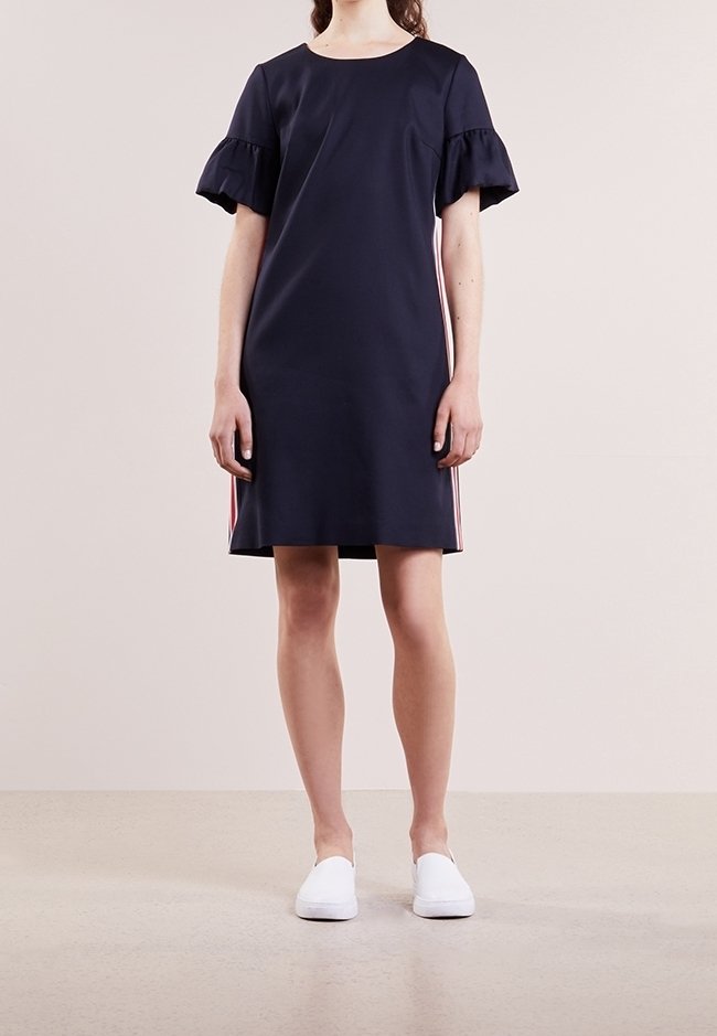 Robe courte marine à manches courtes avec volants, présentant des rayures verticales rouges et blanches sur les côtés. Tissu lisse, design à mi-mollet.