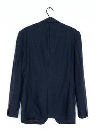 Mörkblå kostymjacka med en slät yta, enkel vent, och svarta knappar. Hänger från en svart krok mot en vit bakgrund.