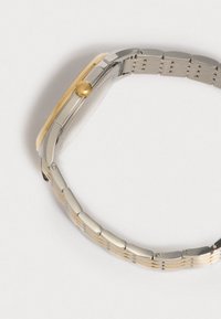 Hopeakylkinen ja kultakylkinen rannekello, jossa on pyöreä kotelo, sileä kehys ja metallinen linkkiranneke, jossa on vaihtelevaa kiillottamista ja harjattuja pintoja.