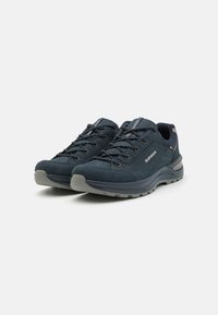 Lage wandelschoenen in donkerblauw suede met grijze rubberen zolen, voorzien van gepadde tongen, gestructureerde veters en versterkte neuzen.
