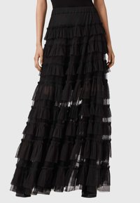 Sort lagdelt maxi-nederdel lavet af lagdelt tylstof, med rynkede kanter og en glat talje, designet til let at svaje med bevægelse.