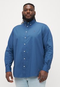 Modrá košeľa na gombíky z hladkej bavlny, s klasickým golierom, dlhými rukávmi a malým logom na hrudi.