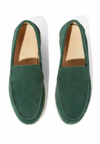 Zelene suknjene cipele bez vezica s okruglim vrhom i minimalnim detaljima šivanja. Mekana tekstura i jednobojne, s svijetlom potplatom.